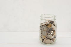 Новые монетки тайского бата в стеклянном опарнике, на белом деревянном столе стоковые фотографии rf Новые монетки тайского бата в стеклянном опарнике, на белом деревянном столе стоковые фотографии rf
