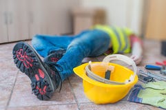 Нога и желтый шлем раненого лежа работника на работе стоковая фотография Нога и желтый шлем раненого лежа работника на работе стоковая фотография