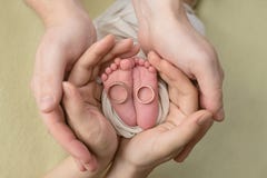 Ноги newborn младенца, пальцы ноги в руках мамы и папа, первые дни жизни после рождения, обручальные кольца семьи стоковая фотография rf Ноги newborn младенца, пальцы ноги в руках мамы и папа, первые дни жизни после рождения, обручальные кольца семьи стоковая фотография rf