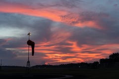 Носок ветра вниз на рассвете под красным оранжевым накаляя небом с облаками цирруса и кумулюса стоковое фото Носок ветра вниз на рассвете под красным оранжевым накаляя небом с облаками цирруса и кумулюса стоковое фото