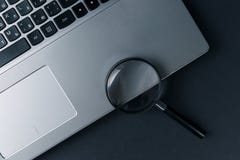 Ноутбук с лупой на темной предпосылке, концепции поиска стоковая фотография Ноутбук с лупой на темной предпосылке, концепции поиска стоковая фотография