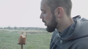 Облыселый, красивый человек в природе ест зажаренный в духовке хлеб зажаренный на ручке над огнем акции видеоматериалы Облыселый, красивый человек в природе ест зажаренный в духовке хлеб зажаренный на ручке над огнем акции видеоматериалы