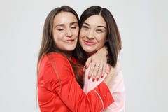 Образ жизни, приятельство и концепция людей - 2 красивых девушки одетой в пижамах обнимая и усмехаясь стоковое изображение Образ жизни, приятельство и концепция людей - 2 красивых девушки одетой в пижамах обнимая и усмехаясь стоковое изображение