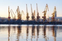 Одесса, Украина - Januadry 02, 2017: Краны в терминале порта груза, краны контейнера груза отразили в воде Заход солнца стоковое изображение rf Одесса, Украина - Januadry 02, 2017: Краны в терминале порта груза, краны контейнера груза отразили в воде Заход солнца стоковое изображение rf