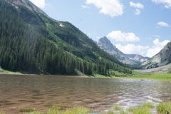 Озеро кратер в Maroon глуши колоколов Snowmass в Aspen Колорадо с голубым небом и облаками в лете стоковая фотография rf Озеро кратер в Maroon глуши колоколов Snowmass в Aspen Колорадо с голубым небом и облаками в лете стоковая фотография rf
