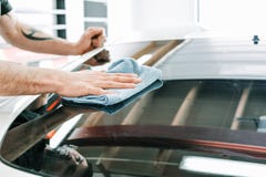Окно человека очищая с голубым половиком подкрашиванного автомобиля стоковая фотография Окно человека очищая с голубым половиком подкрашиванного автомобиля стоковая фотография