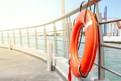 Оранжевое lifebuoy причаленное на перилах дока стоковая фотография Оранжевое lifebuoy причаленное на перилах дока стоковая фотография
