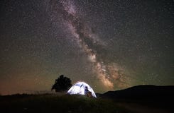 Отдыхать женщины туристский на ноче располагаясь лагерем под звёздным небом и млечным путем стоковая фотография Отдыхать женщины туристский на ноче располагаясь лагерем под звёздным небом и млечным путем стоковая фотография
