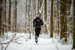 Отображайте от задней части человека в sportswear, красной крышке на беге в зиме стоковое фото Отображайте от задней части человека в sportswear, красной крышке на беге в зиме стоковое фото