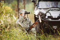 Охотник при корокоствольное оружие смотря через бинокли в лесе стоковая фотография rf Охотник при корокоствольное оружие смотря через бинокли в лесе стоковая фотография rf