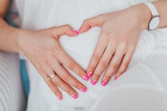 Очаровательный tummy который беременная женщина в белом платье обнимает Беременная девушка с розовым животом обнимать маникюра стоковое изображение rf Очаровательный tummy который беременная женщина в белом платье обнимает Беременная девушка с розовым животом обнимать маникюра стоковое изображение rf