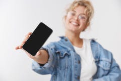 Очаровывая удачливая симпатичная подпитанная молодая белокурая кавказская девушка запачканная за смартфоном камеры шоу руки прост стоковая фотография Очаровывая удачливая симпатичная подпитанная молодая белокурая кавказская девушка запачканная за смартфоном камеры шоу руки прост стоковая фотография
