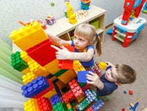 Очень серьезные мальчик и девушка строят большую башню блока Стоковая Фотография RF Очень серьезные мальчик и девушка строят большую башню блока Стоковая Фотография RF
