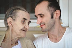 Очень старая старшая женщина сидя в балконе с ее внуком стоковое изображение Очень старая старшая женщина сидя в балконе с ее внуком стоковое изображение