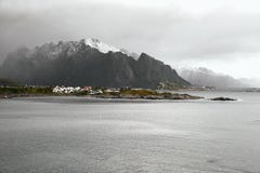 Панорамный вид норвежского побережья и деревни перед snowcapped горной цепью во время зимы на островах Lofoten в никаком стоковое фото rf Панорамный вид норвежского побережья и деревни перед snowcapped горной цепью во время зимы на островах Lofoten в никаком стоковое фото rf