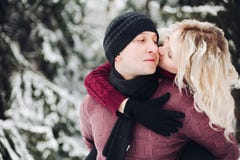 Пары в красных свитерах имея потеху среди идя снег леса и целовать стоковое фото rf Пары в красных свитерах имея потеху среди идя снег леса и целовать стоковое фото rf