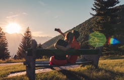Пары сидя на стенде в горах наблюдая заход солнца и принимая selfie стоковая фотография Пары сидя на стенде в горах наблюдая заход солнца и принимая selfie стоковая фотография