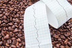Переплетенный тип электрокардиограммы с напечатанной линией ECG лежит на зажаренных кофейных зернах Плотно сожмите кофе и кофеин стоковое фото rf Переплетенный тип электрокардиограммы с напечатанной линией ECG лежит на зажаренных кофейных зернах Плотно сожмите кофе и кофеин стоковое фото rf