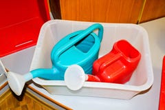Пестротканые пластиковые красные голубые лейки с ручкой для моча заводов, цветков стоковое изображение rf Пестротканые пластиковые красные голубые лейки с ручкой для моча заводов, цветков стоковое изображение rf