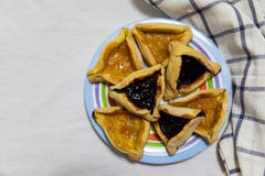 Печенья варенья голубики и абрикоса Hamantash Purim на покрашенной плите с ветошью шотландки голубой и белой предпосылкой листа стоковое фото Печенья варенья голубики и абрикоса Hamantash Purim на покрашенной плите с ветошью шотландки голубой и белой предпосылкой листа стоковое фото