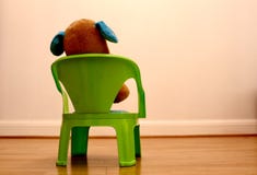 Плюшевый медвежонок сидя на стуле смотря пустую белую стену стоковые фото Плюшевый медвежонок сидя на стуле смотря пустую белую стену стоковые фото