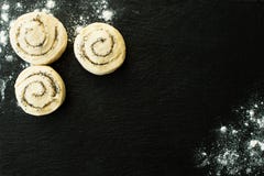 Плюшки с сахаром и маковыми семененами, тестом лежа на черной каменной разделочной доске взбрызнутой с мукой стоковая фотография rf Плюшки с сахаром и маковыми семененами, тестом лежа на черной каменной разделочной доске взбрызнутой с мукой стоковая фотография rf