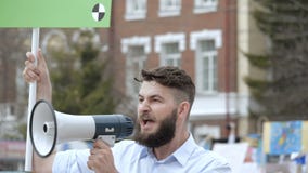 Повстанец на революции кричит в конец-вверх мегафона в замедленном движении Повстанец на революции кричит в конец-вверх мегафона в замедленном движении