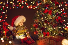 Подарочная коробка младенца рождества открытая присутствующая под деревом Xmas, счастливым ребенк стоковая фотография Подарочная коробка младенца рождества открытая присутствующая под деревом Xmas, счастливым ребенк стоковая фотография