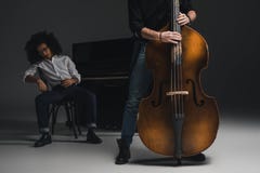 подрезанная съемка человека играя violoncello пока его подавленный партнер сидя на запачканном рояле стоковое фото rf подрезанная съемка человека играя violoncello пока его подавленный партнер сидя на запачканном рояле стоковое фото rf