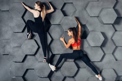 Подходящие женщины представляя как смертная казнь через повешение альпиниста на декоративной стене стоковое изображение Подходящие женщины представляя как смертная казнь через повешение альпиниста на декоративной стене стоковое изображение