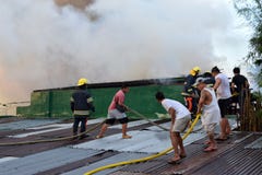 Пожарные и волонтеры на огне положенном крышей вне используя пожарный рукав во время огня дома который опустошал внутреннюю хибар стоковое изображение Пожарные и волонтеры на огне положенном крышей вне используя пожарный рукав во время огня дома который опустошал внутреннюю хибар стоковое изображение