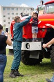 Пожарный кладет дальше шлем огня на мальчика который стоит дальше стоковые фотографии rf Пожарный кладет дальше шлем огня на мальчика который стоит дальше стоковые фотографии rf