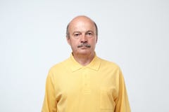 Пожилые эмоции человека, портрет серьезного старшего кавказского человека смотря камеру против серой стены стоковая фотография rf Пожилые эмоции человека, портрет серьезного старшего кавказского человека смотря камеру против серой стены стоковая фотография rf