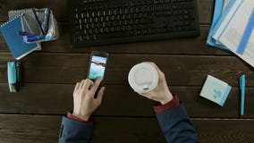 Покройте вниз с взгляда человека выбирая новые обои на его мобильном телефоне Покройте вниз с взгляда человека выбирая новые обои на его мобильном телефоне
