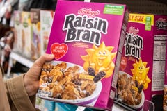 Покупатели вручают удержание коробки отрубей изюминки бренда kellogg стоковое изображение rf Покупатели вручают удержание коробки отрубей изюминки бренда kellogg стоковое изображение rf