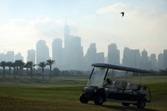 Поле для гольфа в Дубай с птицей, golfcart и небоскребами на заднем плане стоковая фотография rf Поле для гольфа в Дубай с птицей, golfcart и небоскребами на заднем плане стоковая фотография rf