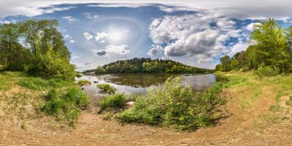 Полностью безшовная сферически панорама 360 градусов взгляда угла на береге широкого neman реки с венчиком и красивыми облаками в стоковое фото rf Полностью безшовная сферически панорама 360 градусов взгляда угла на береге широкого neman реки с венчиком и красивыми облаками в стоковое фото rf