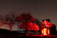 Получившаяся отказ церковь с внутренностью красного света и зацветая nightscape деревьев близрасположенным стоковая фотография Получившаяся отказ церковь с внутренностью красного света и зацветая nightscape деревьев близрасположенным стоковая фотография