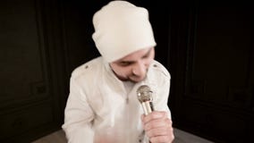 Поп утеса вокалиста подставного лица со стильной бородой в белых одеждах и шляпе с микрофоном в его руках выразительно видеоматериал Поп утеса вокалиста подставного лица со стильной бородой в белых одеждах и шляпе с микрофоном в его руках выразительно видеоматериал