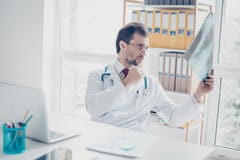Портрет доктора смотря рентгенографирование Он сфокусирован, le стоковое изображение rf Портрет доктора смотря рентгенографирование Он сфокусирован, le стоковое изображение rf