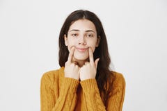 Портрет конца-вверх утомленной и хмурой кавказской прокалыванной девушки протягивая рот с пальцами, делая поддельную улыбку пока стоковые фотографии rf Портрет конца-вверх утомленной и хмурой кавказской прокалыванной девушки протягивая рот с пальцами, делая поддельную улыбку пока стоковые фотографии rf