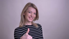 Портрет крупного плана взрослой привлекательной белокурой кавказской женщины показывая большой палец руки вверх по смотреть камер сток-видео Портрет крупного плана взрослой привлекательной белокурой кавказской женщины показывая большой палец руки вверх по смотреть камер сток-видео