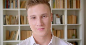Портрет крупного плана молодого уверенного кавказского студента усмехаясь жизнерадостно смотрящ камеру в библиотеке колледжа акции видеоматериалы Портрет крупного плана молодого уверенного кавказского студента усмехаясь жизнерадостно смотрящ камеру в библиотеке колледжа акции видеоматериалы