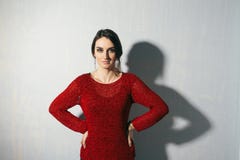Портрет молодой женщины стоя на голубой предпосылке с талией рук стоковая фотография Портрет молодой женщины стоя на голубой предпосылке с талией рук стоковая фотография