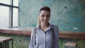 Портрет молодой красивой кавказской женщины в современном coworking космосе Коммерсантка смотря камеру, усмехаясь, сток-видео Портрет молодой красивой кавказской женщины в современном coworking космосе Коммерсантка смотря камеру, усмехаясь, сток-видео
