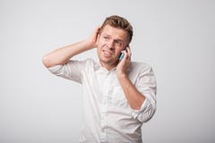 Портрет молодого кавказского неуверенного человека используя мобильный телефон на серой предпосылке стоковые фотографии rf Портрет молодого кавказского неуверенного человека используя мобильный телефон на серой предпосылке стоковые фотографии rf