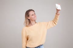 Портрет молодой белокурой усмехаясь женщины используя сотовый телефон, она делает selfie ее телефоном o представления против стоковое изображение rf Портрет молодой белокурой усмехаясь женщины используя сотовый телефон, она делает selfie ее телефоном o представления против стоковое изображение rf
