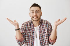 Портрет очаровательной европейской мужской модели в стеклах shrugging и показывая зубы пока стоять с распространением поднял ладо стоковые фото Портрет очаровательной европейской мужской модели в стеклах shrugging и показывая зубы пока стоять с распространением поднял ладо стоковые фото