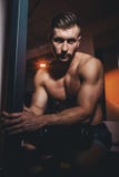 Портрет очень мышечной без рубашки мужской модели Красивый атлетический человек при большие мышцы представляя на камере в спортза стоковые фотографии rf Портрет очень мышечной без рубашки мужской модели Красивый атлетический человек при большие мышцы представляя на камере в спортза стоковые фотографии rf