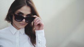 Портрет привлекательной молодой женщины усмехаясь на пляже извлекает солнечные очки крутые акции видеоматериалы Портрет привлекательной молодой женщины усмехаясь на пляже извлекает солнечные очки крутые акции видеоматериалы